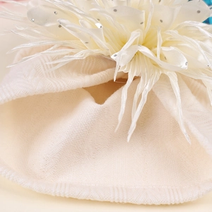 Detail der Babymütze mit cremefarbener Strickstruktur und großer weißer Stoffblume mit Pailletten