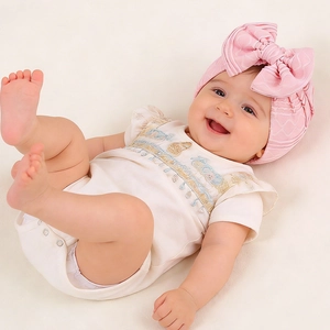 Close-up of baby romper with bohemian embroidery and matching oversized bow headband