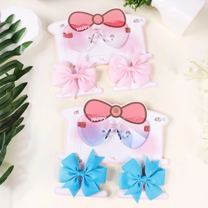 Detailed view of heart-shaped gradient sunglasses and bow hair clips for girls