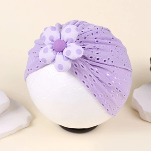 Detailed view of purple hollow knit baby turban hat with a large polka dot floral ornament