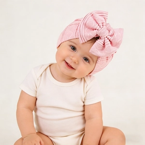 Detail showing the soft pink knit texture and large multilayer bow on the infant turban