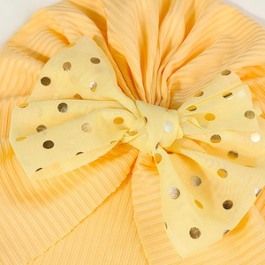 Detailansicht eines gelben Falten-Babyturbans mit goldgepunkteter Schleife