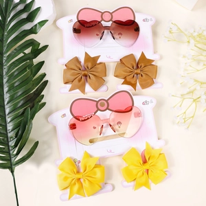 Macro detail of kids heart sunglasses and matching bow hair clips on pink card