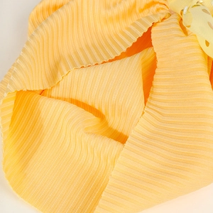 Detailansicht eines gelben Rippstrick-Babyturbans mit goldgepunkteter Schleife