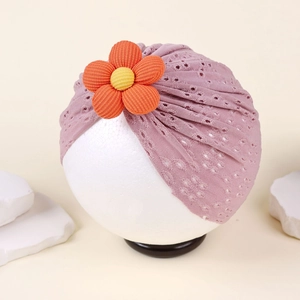 Detail of baby turban hat featuring breathable hollow eyelet fabric and 3D orange flower