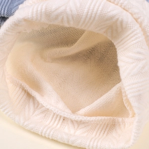 Détail du bonnet tricoté crème pour nouveau-né montrant la texture et la doublure chaude