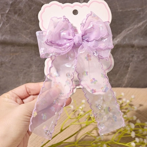 Detail einer lila Spitzen-Haarschleife mit bunten Blumenprints und Perlenquasten