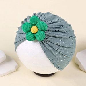 Detail of baby turban hat featuring blue hollow mesh fabric and a green floral applique