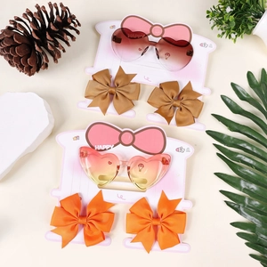 Flat lay of heart-shaped sunglasses and ribbed bow hair clips set for young girls