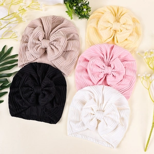 Detail showing jacquard bow turban hats in beige, yellow, black, pink, and white colors