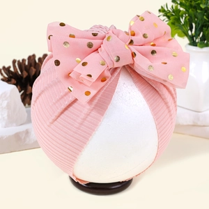 Detail der Strickstruktur des rosa Baby-Turban-Huts mit goldener Polka-Dot-Schleife