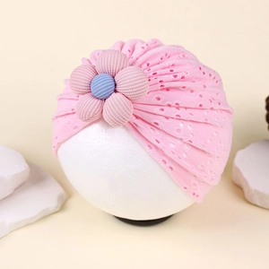 Detail view of pink baby turban hat featuring hollow lace fabric and 3D floral decoration
