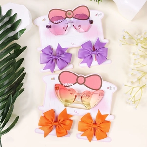 Detail view of heart-shaped gradient sunglasses and matching bow hair clips for kids