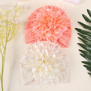 Detail von Baby-Mützen in Koralle und Creme mit großer 3D-Blume und Glitzerelementen