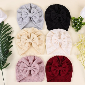 Vue détaillée de six bonnets pour bébé avec nœud en maille gaufrée et décorations végétales