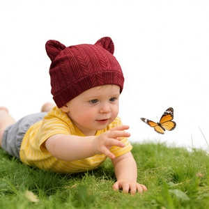 Bébé portant un bonnet en tricot avec oreilles d'ours jouant sur l'herbe avec papillon
