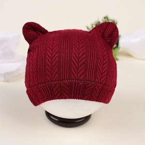 Détails du tricot et oreilles d'ours d'un bonnet pour nouveau-né rouge bordeaux