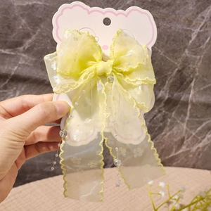 Detail einer gelben Organza-Haarschleife mit Pailletten und Perlenquasten auf Karte