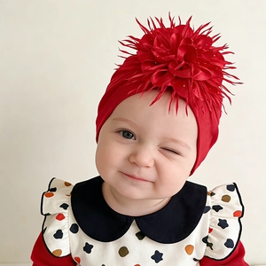 Detail of baby turban hat featuring a large red layered flower and soft knit fabric