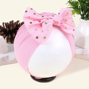 Detailansicht der rosa gerippten Babyhaube mit einer goldenen Chiffon-Punkte-Schleife