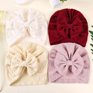 Vue à plat de quatre bonnets turbans côtelés pour bébés avec grands nœuds et couleurs douces