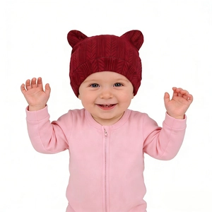 Détail du bonnet tricoté bordeaux pour bébé avec oreilles d'ours et texture de feuilles
