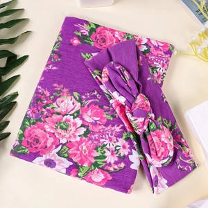 Couverture d'emmaillotage fleurie violette et bandeau à nœud assorti sur fond blanc épuré