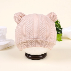 Détail du bonnet tricoté bébé avec oreilles d'ours, texture chevrons beige sur support