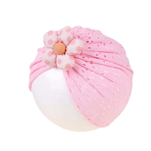 Pink breathable hollow lace baby turban hat with a large polka dot flower on white background