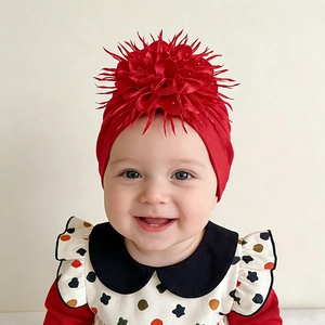 Close-up of baby turban hat featuring a large red decorative flower and soft knit fabric