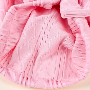 Close-up of pink knit baby hat featuring intricate hollow diamond weave and elastic edge