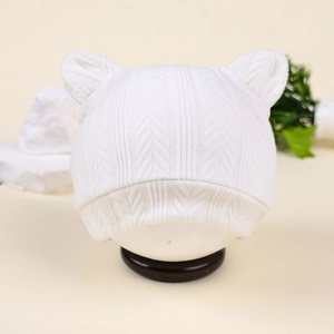 Vue détaillée du bonnet en tricot blanc pour bébé avec oreilles d'ours et texture