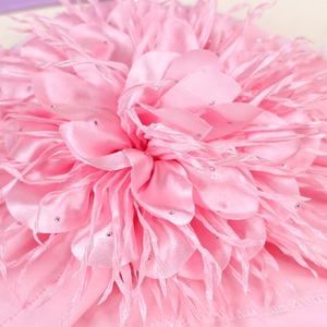 Macro view of soft pink satin flower petal layers with feathers and sparkling rhinestones