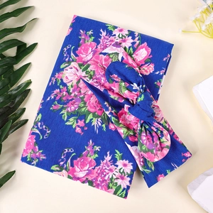 Détail de la couverture d'emmaillotage fleurie bleu foncé et du bandeau à nœud pour nouveau-né