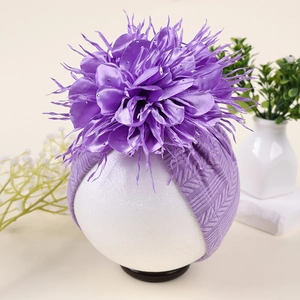 Detailansicht eines lila Babyturbans mit einer großen Kamelienblüte und silbernen Glitzersteinen