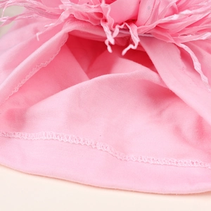 Detail of pink baby beanie showing soft knit fabric and decorative feather trim finish