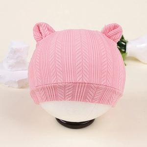 Détail du bonnet en tricot rose pour bébé avec oreilles d'ours et motif chevronné