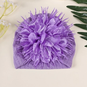 Detail einer lila Baby-Strickmütze mit großer Satinblume und glitzernden Strasssteinen