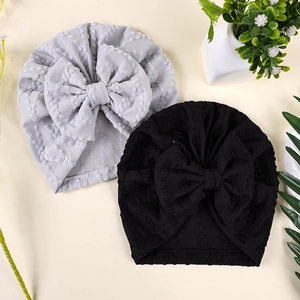 Détail de bonnets en tricot pour bébé avec nœuds montrant le tissu gaufré et la couture