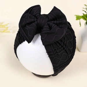 Detailed close-up of black newborn turban hat featuring a large bow and textured knit fabric