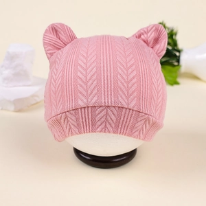 Gros plan d'un bonnet en tricot rose pour bébé avec oreilles d'ours et rayures verticales