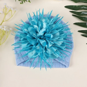 Makroaufnahme einer Baby-Turbanmütze mit großer blauer Kamelienblüte und Strasssteinen