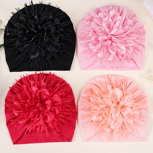 Detail view of baby turban hats with large shiny flower petals in four various colors
