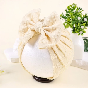 Détail du bonnet turban pour bébé en tricot gaufré crème avec décoration gros nœud souple