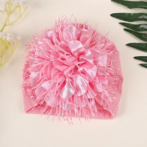 Nahaufnahme der rosa Baby-Strickmütze mit großer Satin-Kamelienblüte und glänzenden Strass