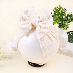 Détail de la texture du bonnet turban en maille gaufrée avec grand nœud pour bébé