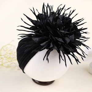 Détail du bandeau turban noir orné d'une grande fleur multicouche et de paillettes