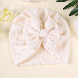 Détail du bonnet turban pour bébé beige avec texture à pois et grand nœud décoratif