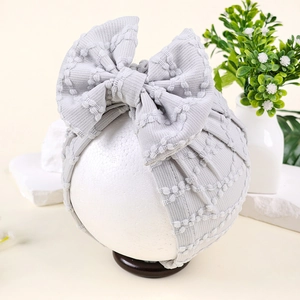 Détail macro d'un bonnet turban gris clair pour bébé en maille gaufre avec un nœud
