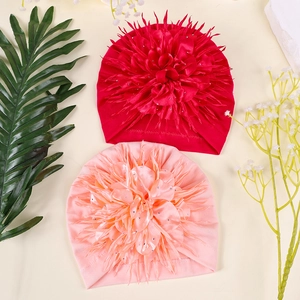 Detailed view of baby turban hats with large satin flowers and sparkling rhinestones